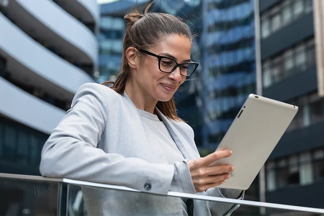 smiling woman with a tablet on the terrace of a building in a city