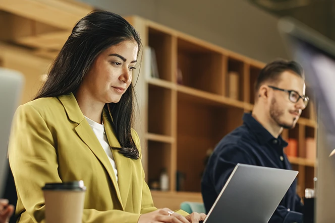 2 pessoas a trabalhar em computadores, num escritório