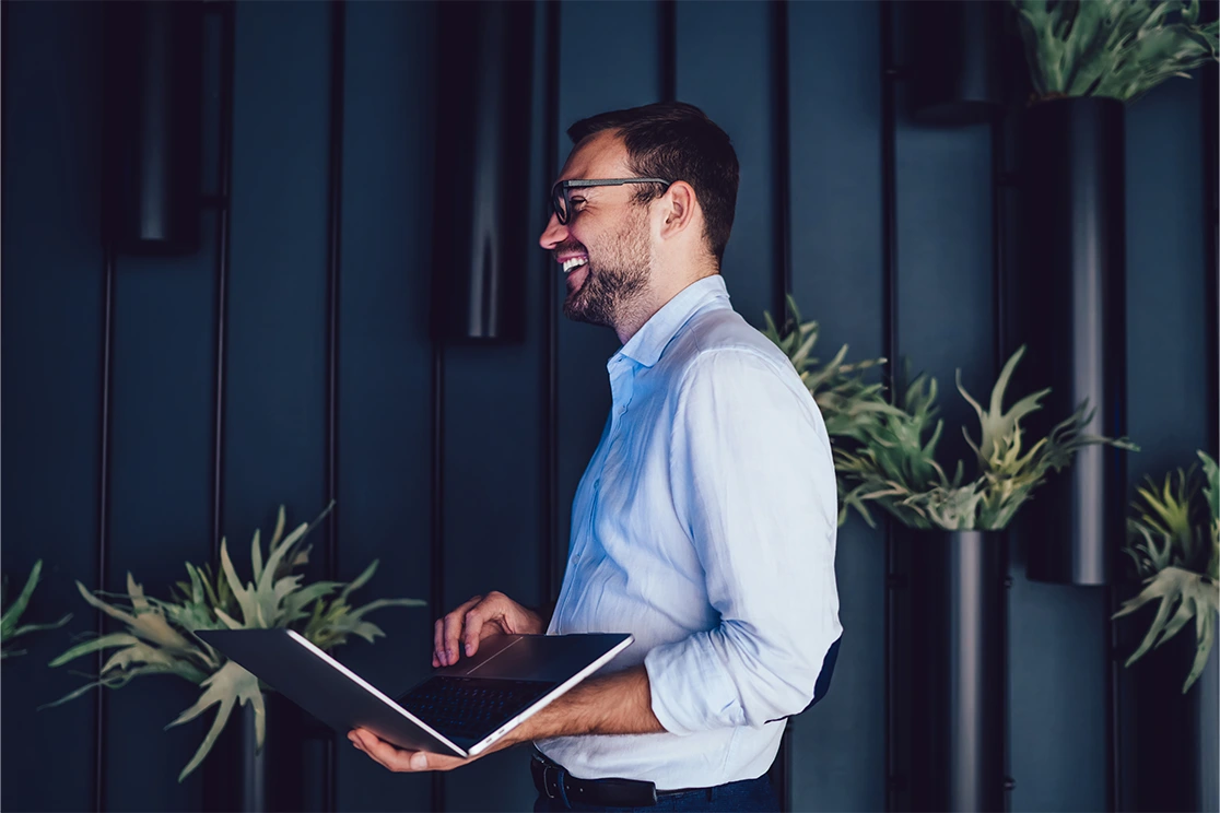 man standing and smilling, with laptop