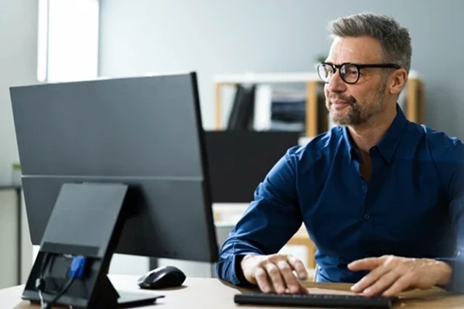 Homem de óculos a usar um computador num escritório