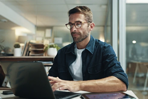 homem sentado, a trabalhar num computador, na sua sala
