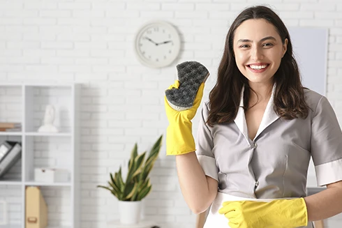 empregada doméstica sorridente, com luvas e um esfregão na mão