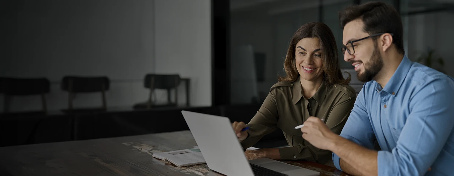 man and woman sitting in front of a computer, talking