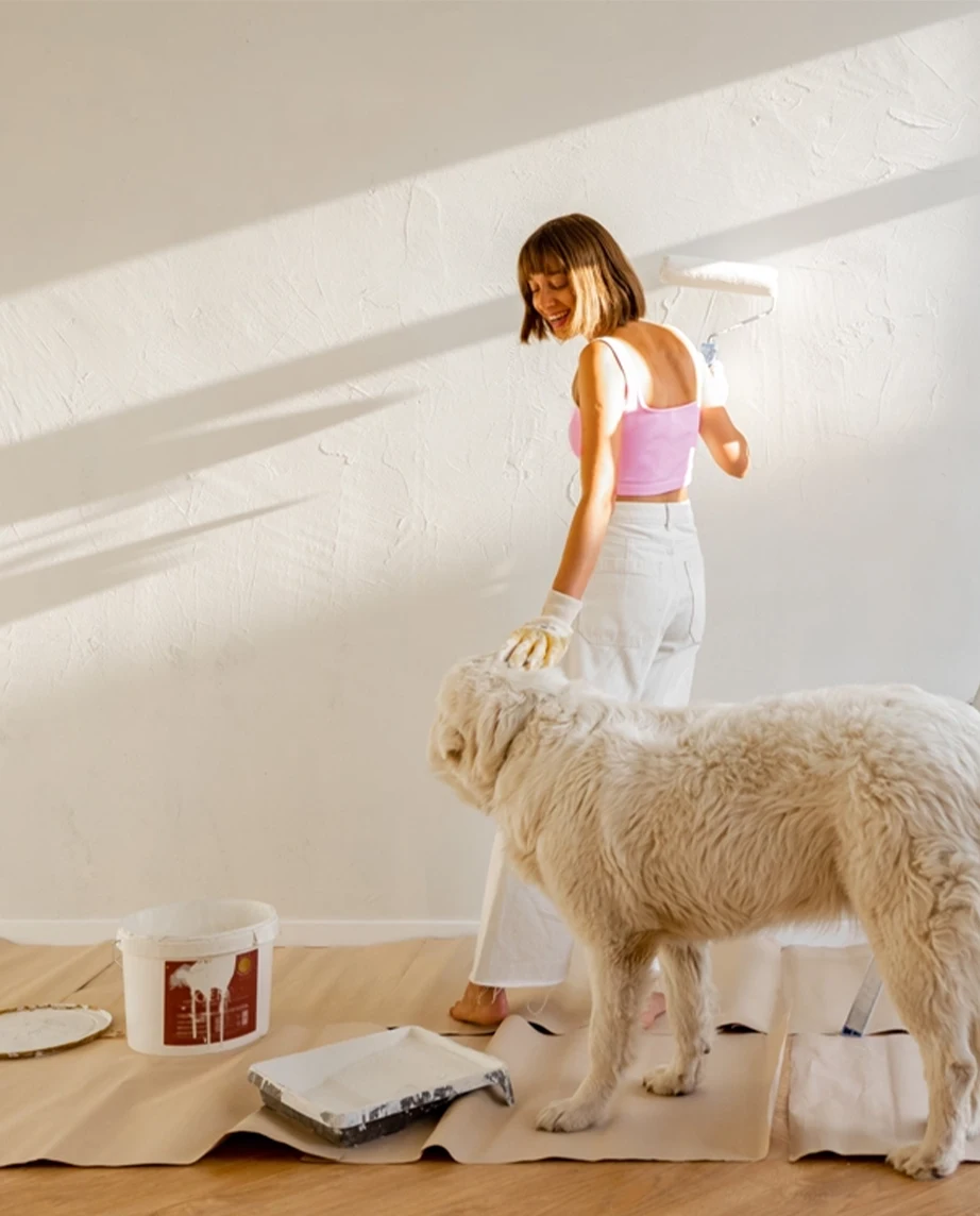 Senhora acompanhada de cão, a pintar uma parede de casa