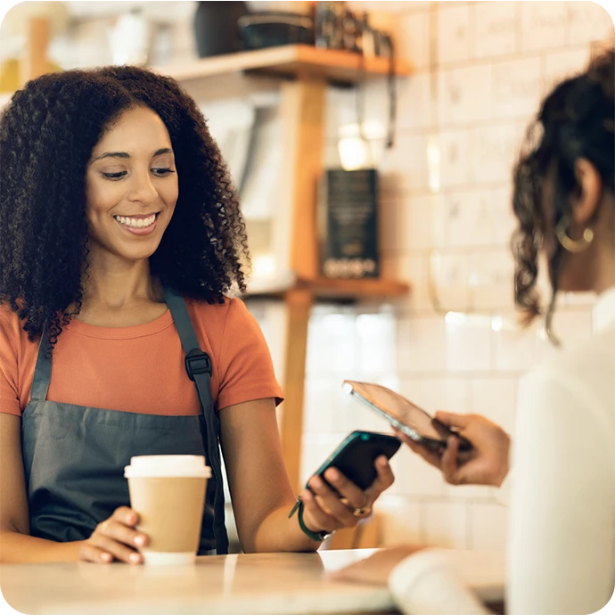 senhora sorridente, com avental, a segurar TPA onde está a ser feito um pagamento