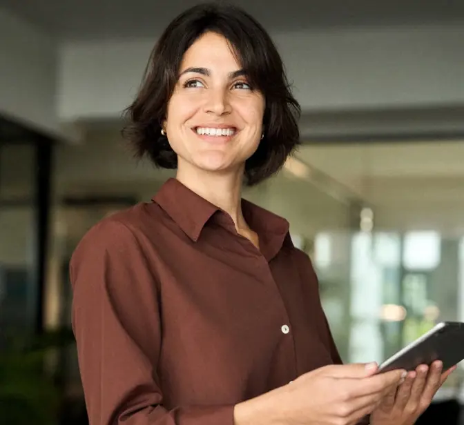 Mulher sorridente com tablet na mão, a olhar para cima num escritório