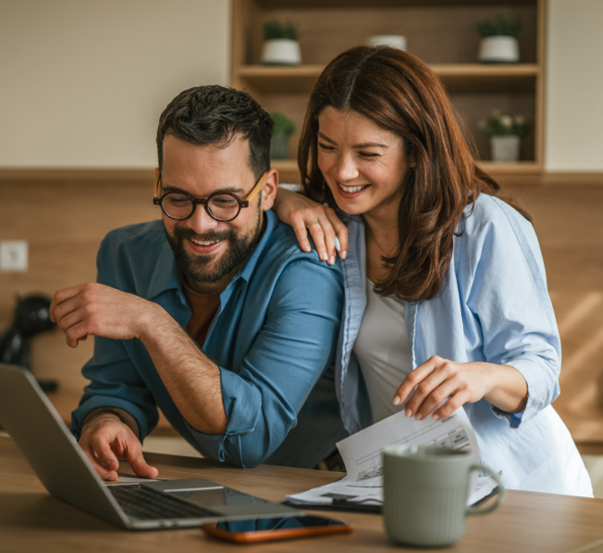 Casal sorridente a usar o portátil na cozinha
