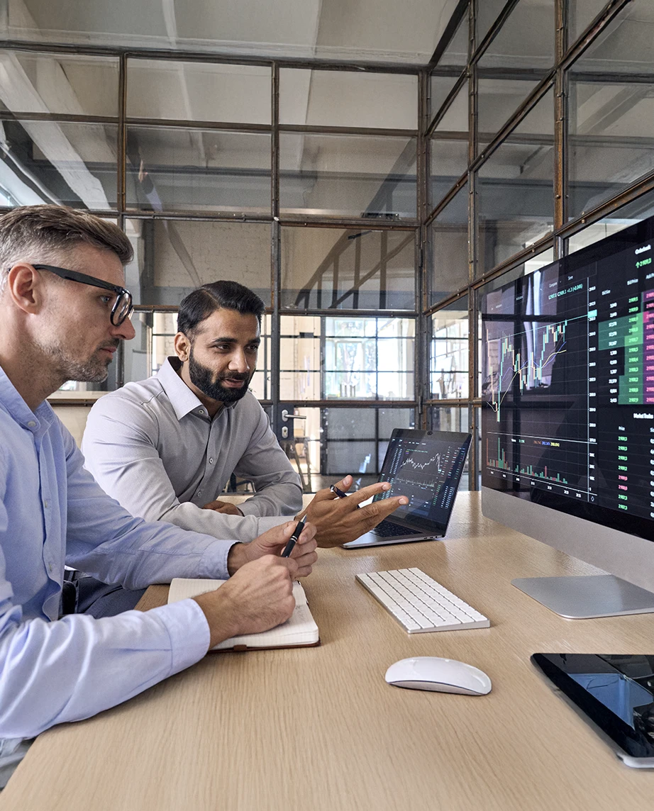 Dois colegas, no local de trabalho, com o computador aberto, a conversarem sobre Depósitos Estruturados