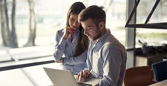 mulher e homem com laptop, a conversar e olhar para o ecrã