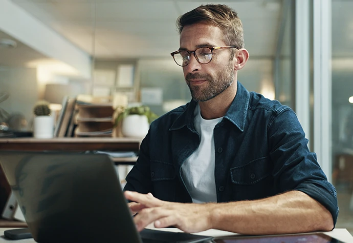 homem sentado, a trabalhar num computador, na sua sala