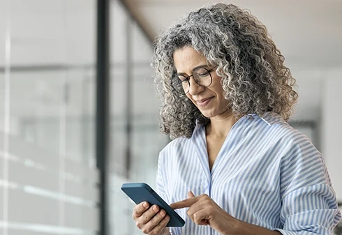 Mulher de cabelo grisalho usa o telemóvel num escritório
