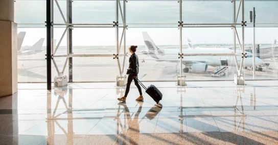 Mulher com mala de viagem a caminhar num terminal de aeroporto