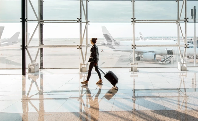 Mulher com mala de viagem a caminhar num terminal de aeroporto
