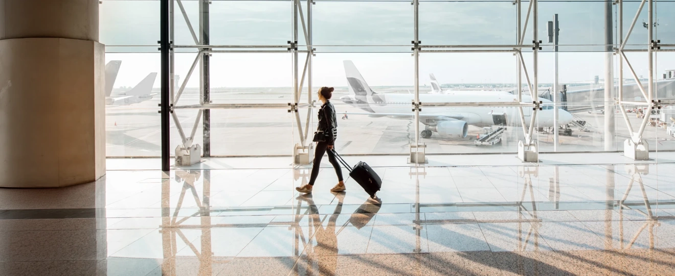 Mulher com mala de viagem a caminhar num terminal de aeroporto