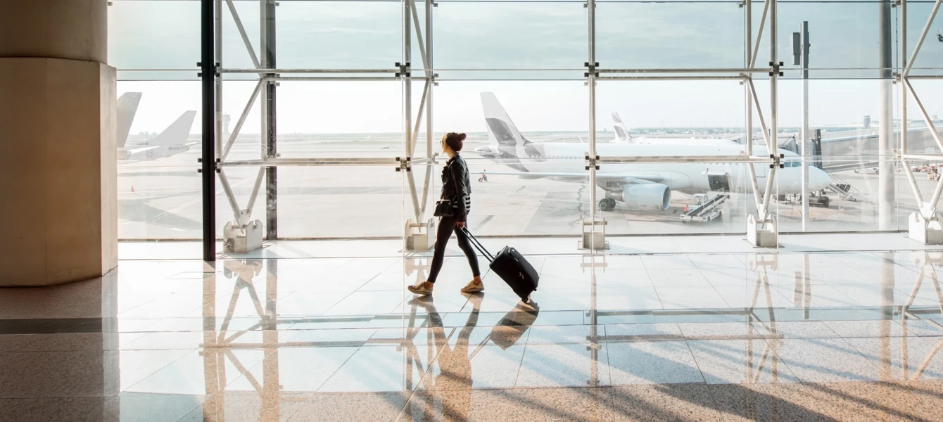 Mulher com mala de viagem a caminhar num terminal de aeroporto