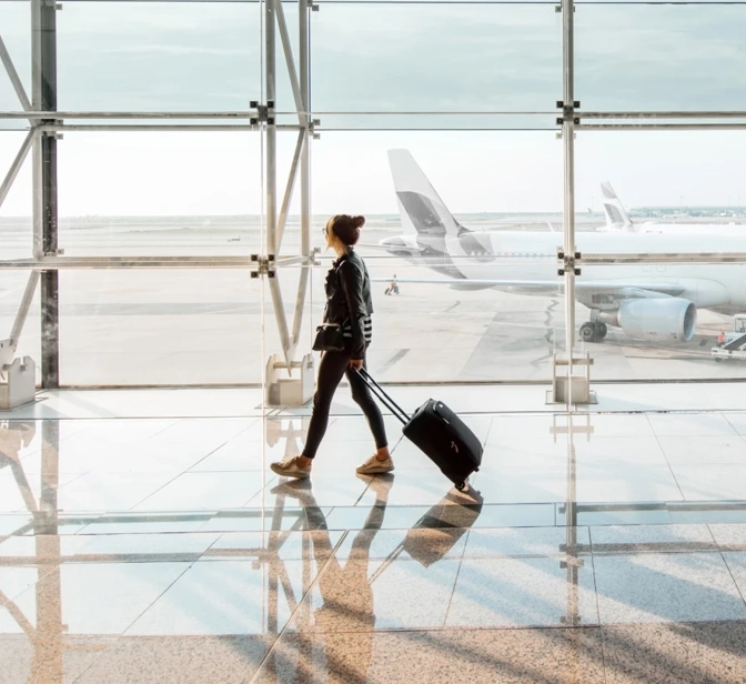 Mulher com mala de viagem a caminhar num terminal de aeroporto