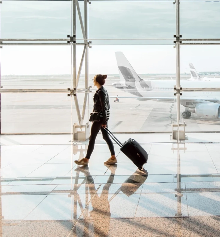 Mulher com mala de viagem a caminhar num terminal de aeroporto
