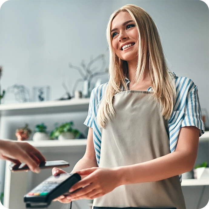 senhora sorridente, com avental, a segurar TPA onde está a ser feito um pagamento