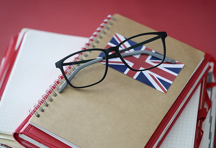 caderno com bandeira Britânica, e óculos por cima