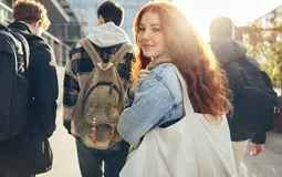 girl student, walking down the street with a bag over her shoulder