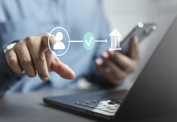 Person digitally validating identity to access the bank via mobile phone and laptop