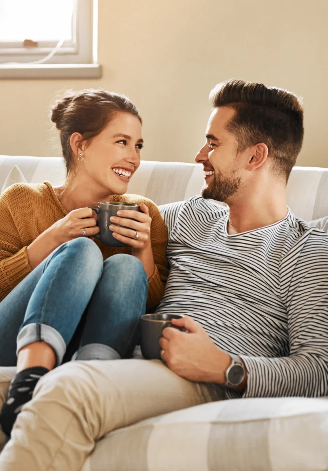 Casal no sofá sorridente com uma chávena de café