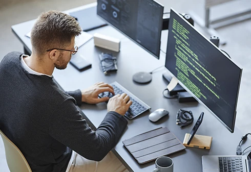 Homem sentado numa secretária e a usar o teclado de um computador