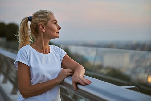 woman leaning on a balcony, looking at the horizon