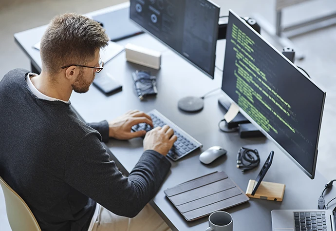 Homem sentado numa secretária e a usar o teclado de um computador