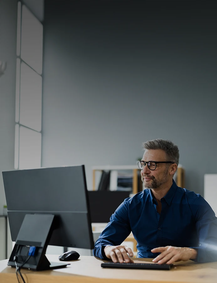 homem sentado, a trabalhar num computador, num escritório