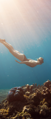 mulher a nadar debaixo de água perto do fundo do mar