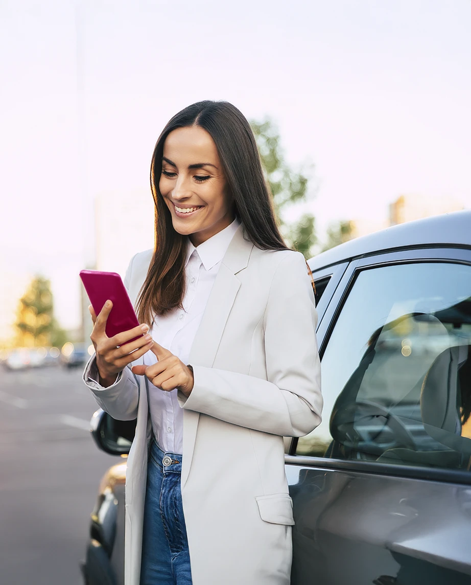 senhora com telemóvel, ao lado do seu carro
