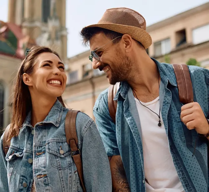 Casal sorridente com mochilas a passear numa cidade histórica