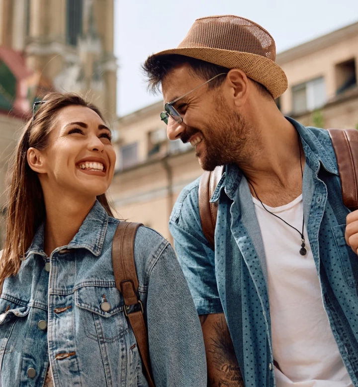 Casal sorridente com mochilas a passear numa cidade histórica
