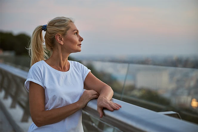 woman leaning on a balcony, looking at the horizon
