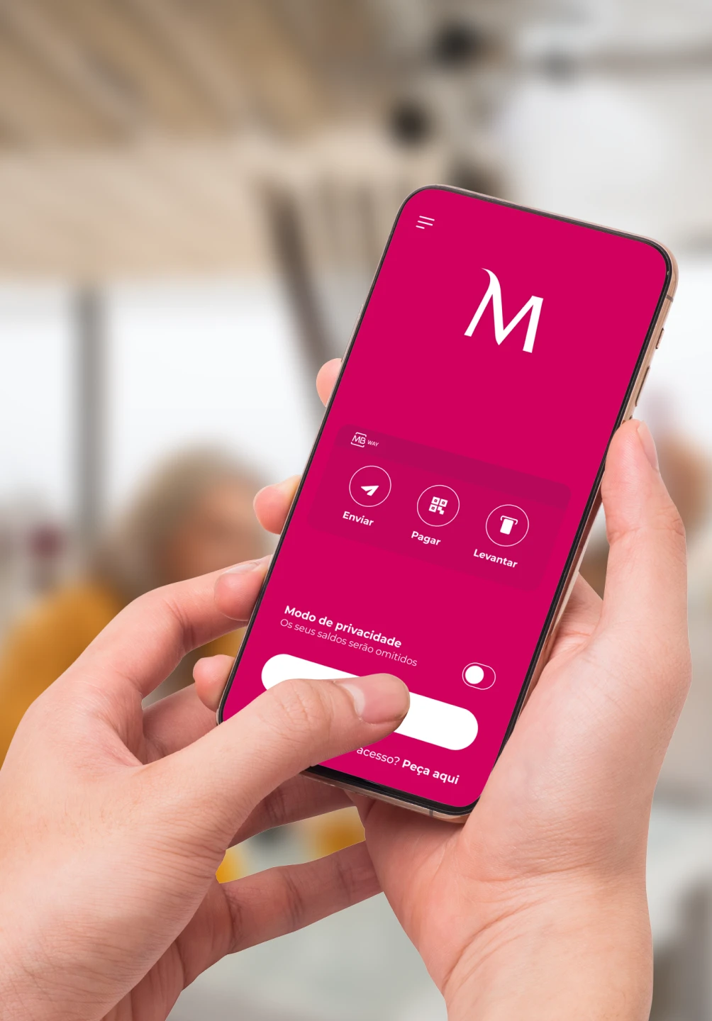 Mãos a agarrar um smartphone que apresenta o ecrã de pré-login da App Millennium