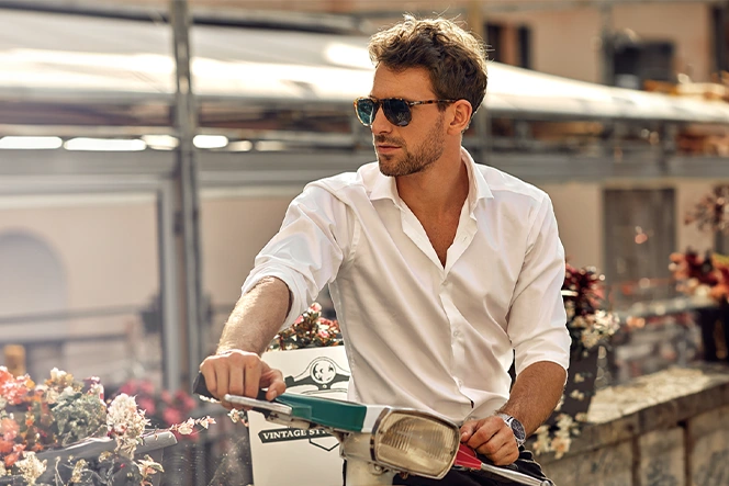 man in a scooter, next to a wall with flowers