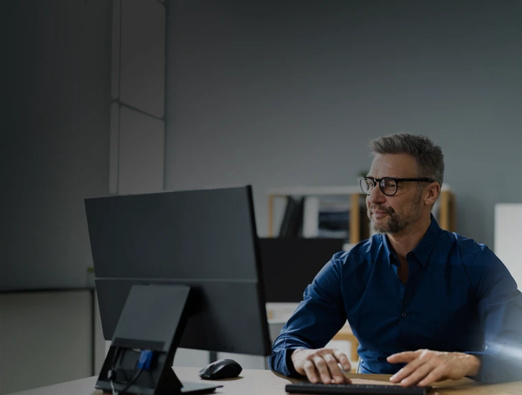 homem sentado, a trabalhar num computador, num escritório