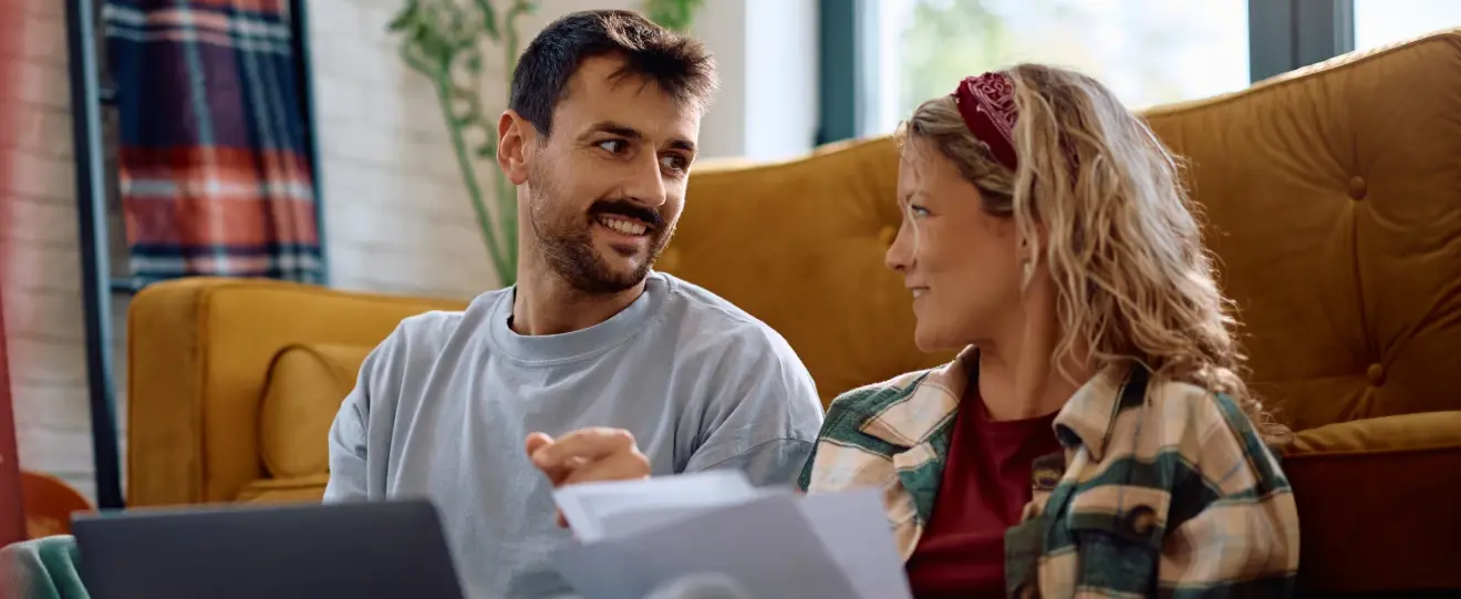 Casal a discutir documentos e a usar um portátil em casa