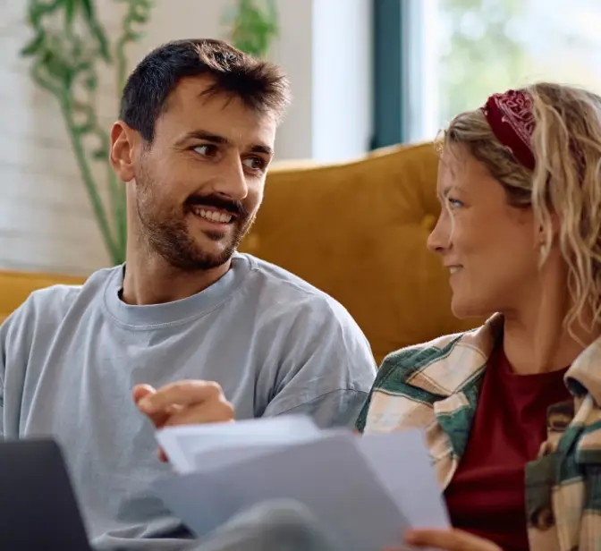 Casal a discutir documentos e a usar um portátil em casa