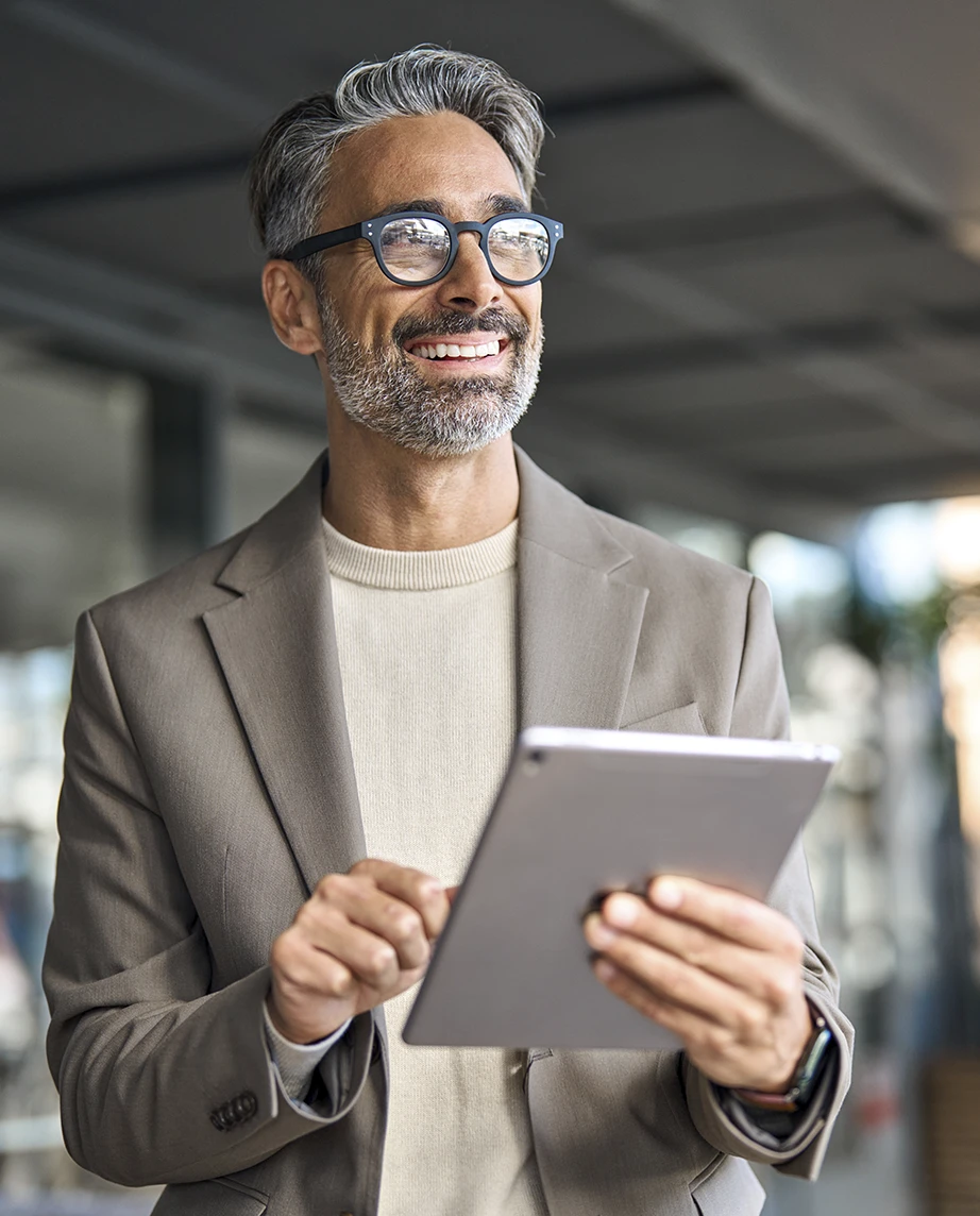 Grey-haired man with glasses, outside a building, holding a tablet