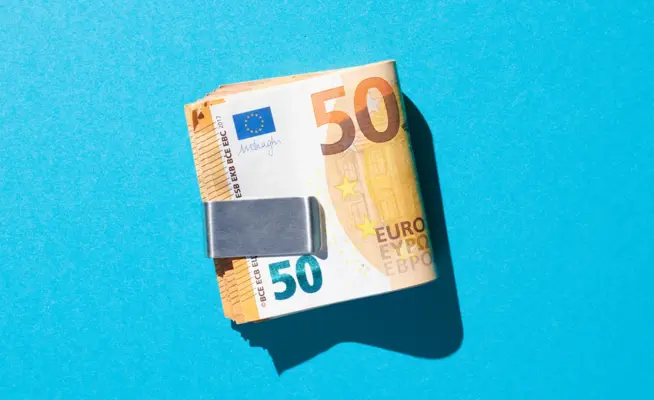 Maço de notas de 50 euros presas por um clipe de dinheiro em fundo azul