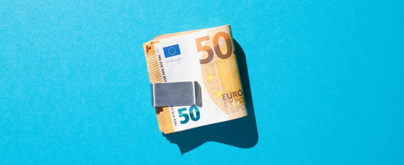 Maço de notas de 50 euros presas por um clipe de dinheiro em fundo azul