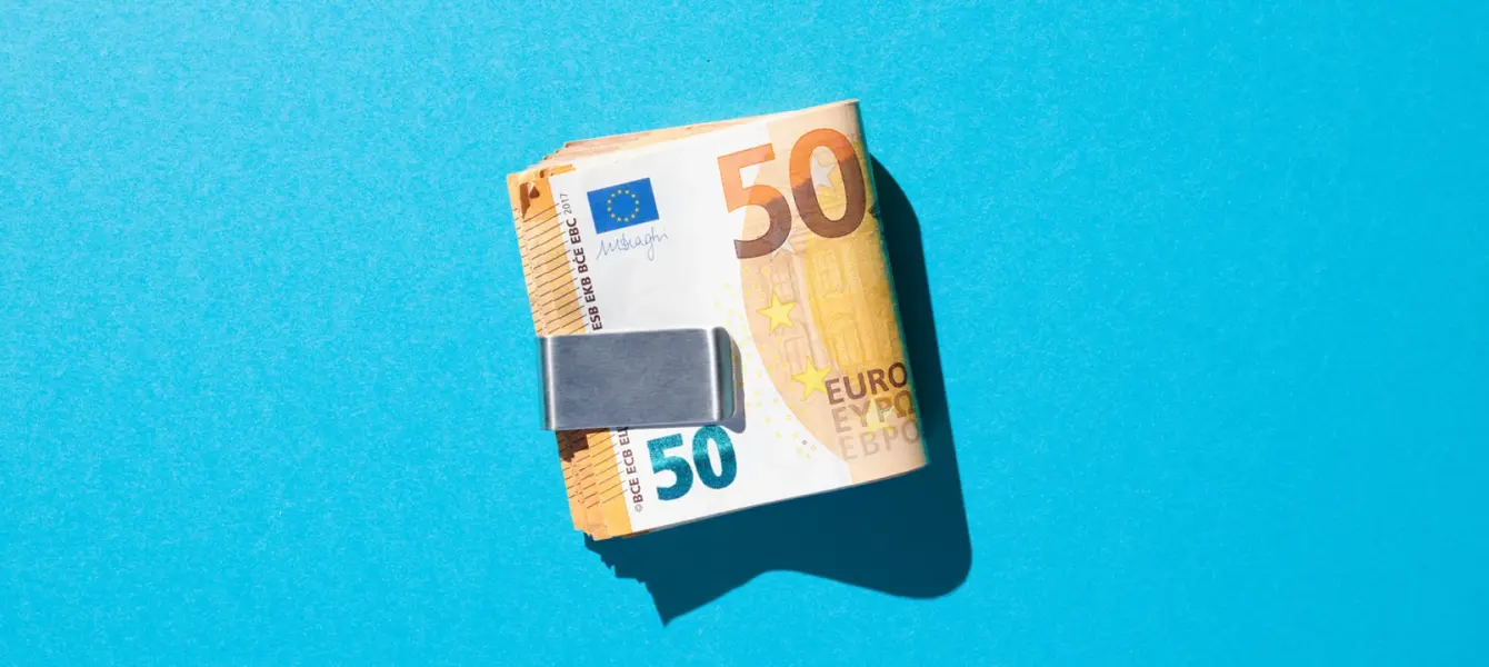 Maço de notas de 50 euros presas por um clipe de dinheiro em fundo azul