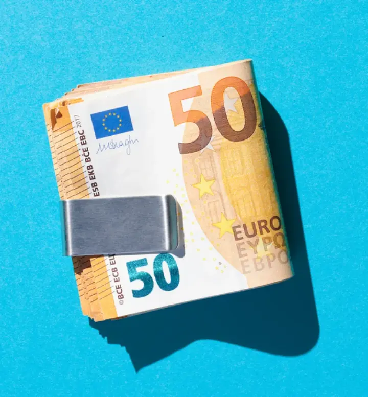 Maço de notas de 50 euros presas por um clipe de dinheiro em fundo azul