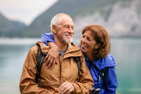 casal maduro a passear junto a lago e montanha