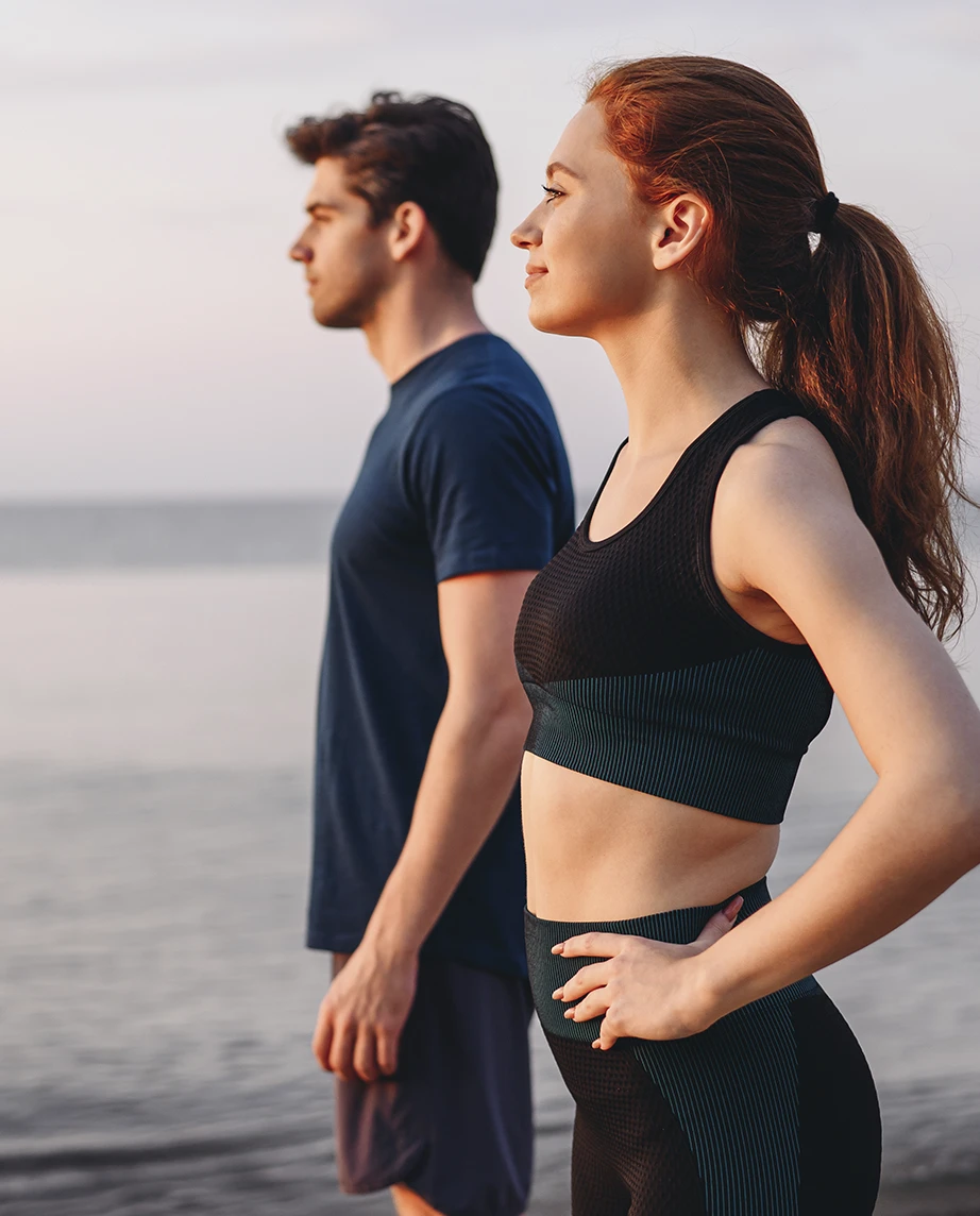 casal jovem, vestidos com roupa desportiva, à beira mar