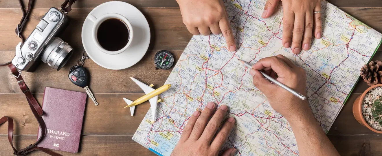 Pessoas a planear uma viagem num mapa com objetos de viagem à volta