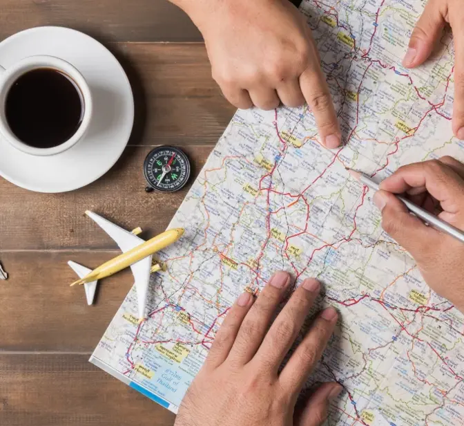 Pessoas a planear uma viagem num mapa com objetos de viagem à volta