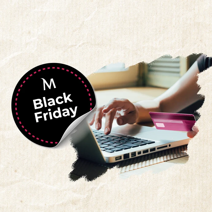 “M Black Friday” e uma pessoa a usar um computador portátil, segurando um cartão de crédito, simbolizando compras online